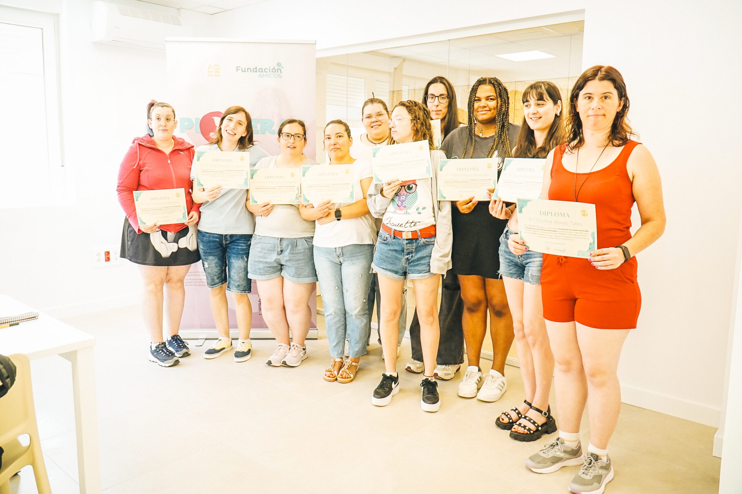 A group of women standing togethr holding up papers