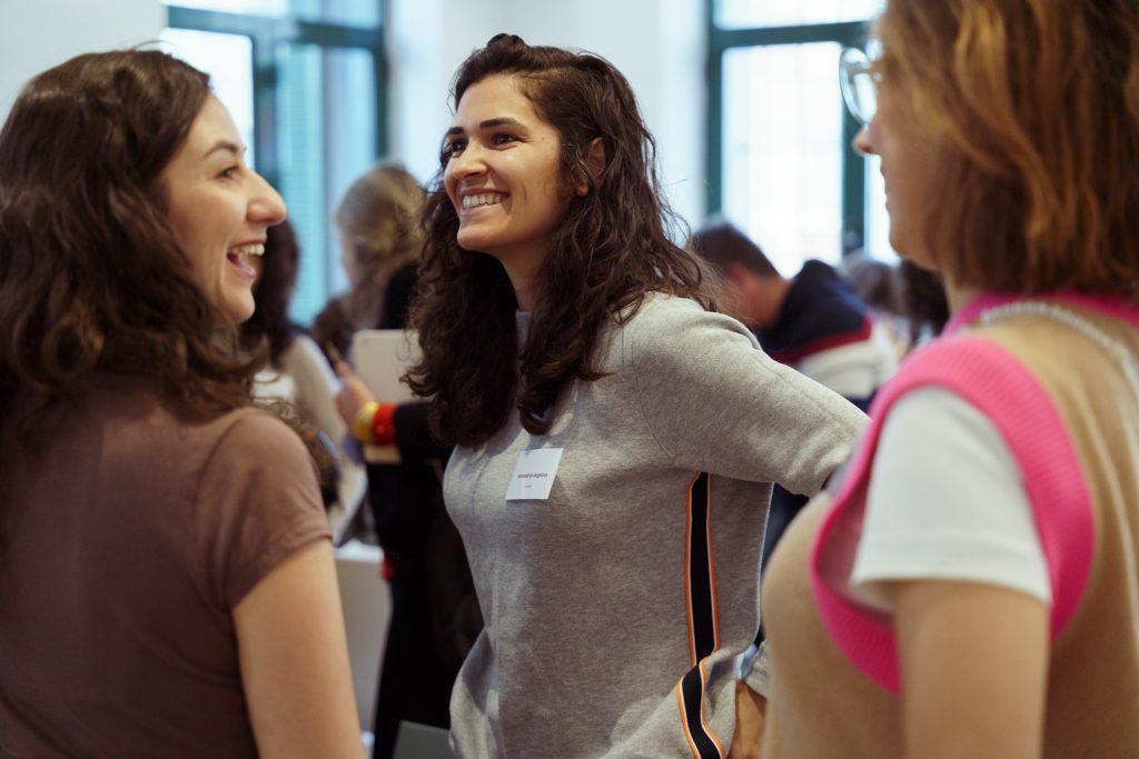 Three women talking together. One is particularly smiling