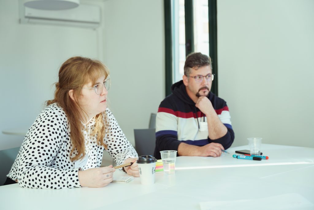 Two people listening carefully sitted on a table