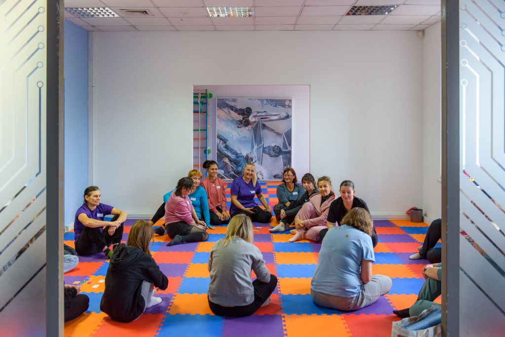 Women sitting on circle on a rubber floor.