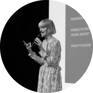 Woman on stage talking on a microphone. Photo in black and white.