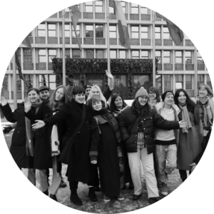 Group of women smiling at the camera in front of an official building. Photo in black and white.