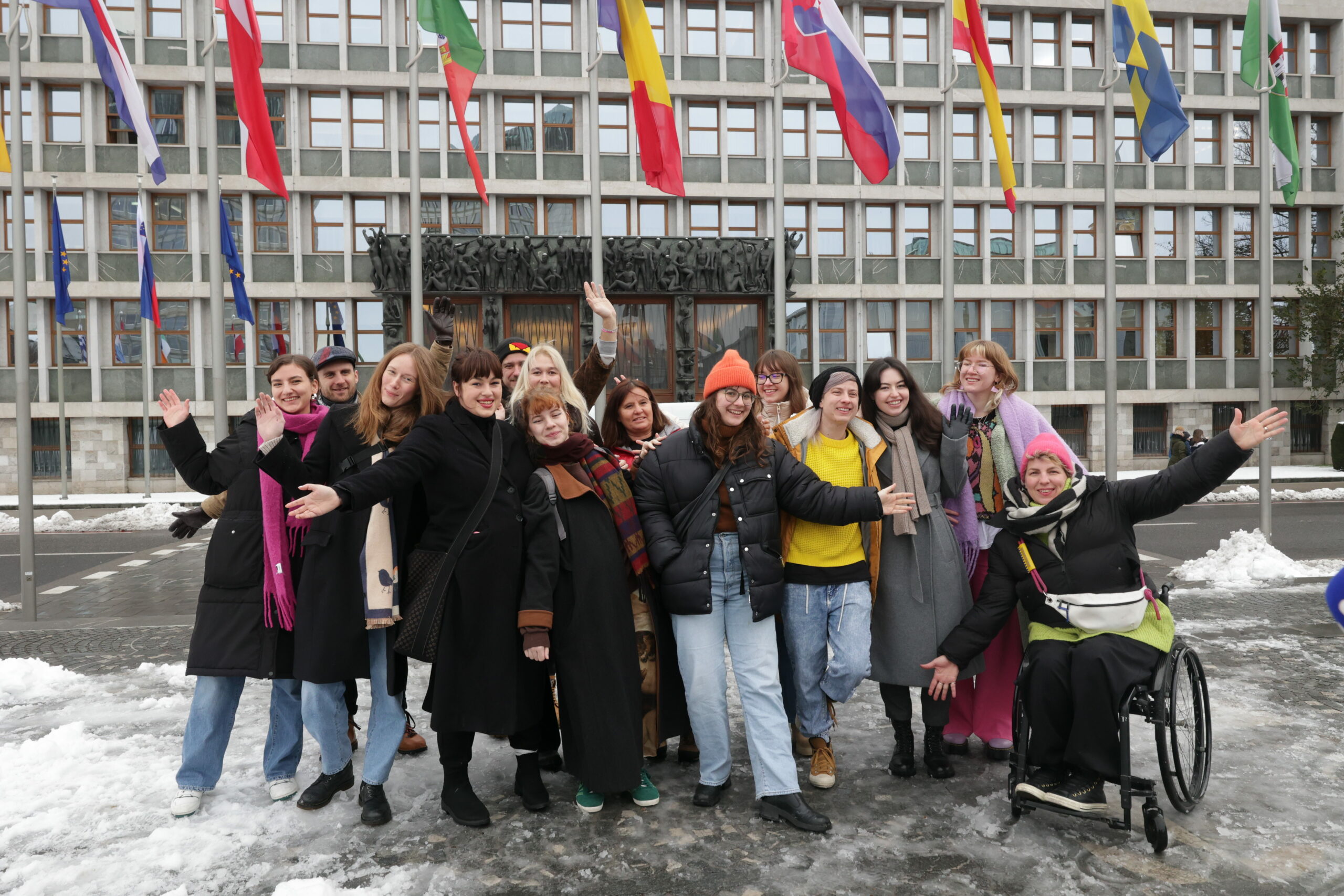 A group standing together with their arms raised in front of the Slovenian parliament.