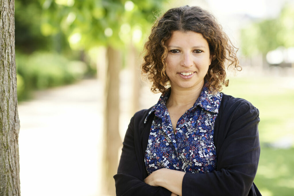 A person stands with crossed arms and smiling.